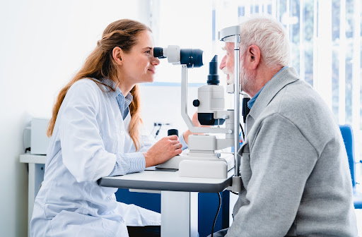 A female optometrist examining an older man's eyes